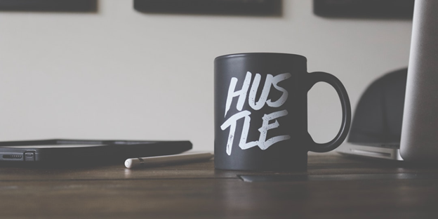 mug with the word "hustle" on front, sitting on desk