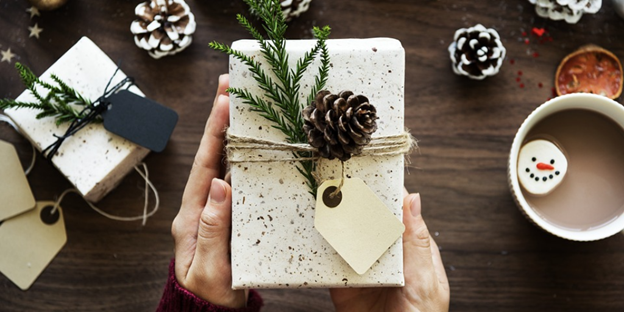 woman holding Christmas gift over table with Christmas decor