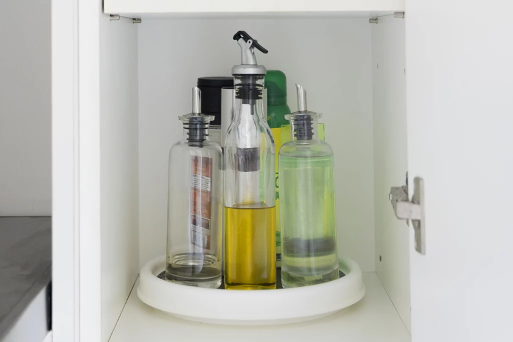 Lazy Susan in a kitchen cabinet holding a variety of oils.