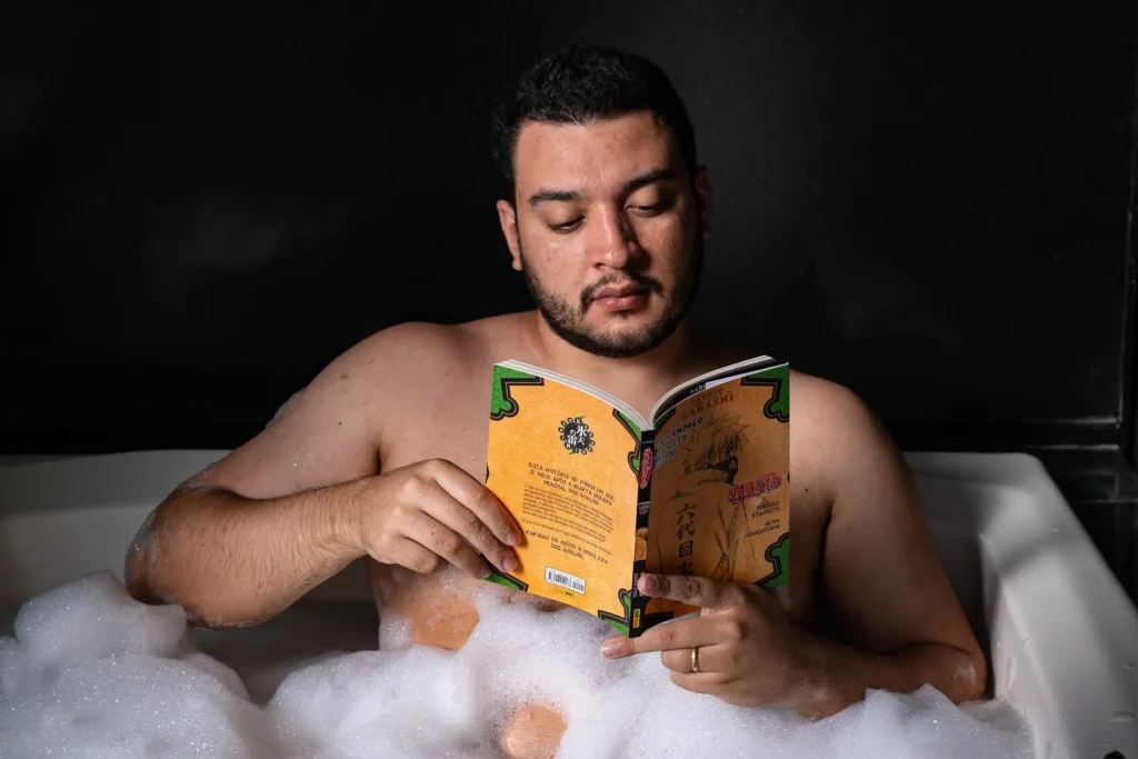 Man reads Naruto book in bubble bath to relax.