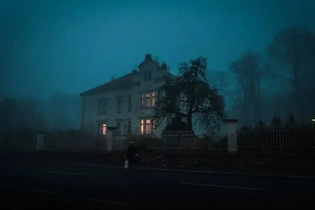 haunted house with glowing windows on a foggy night