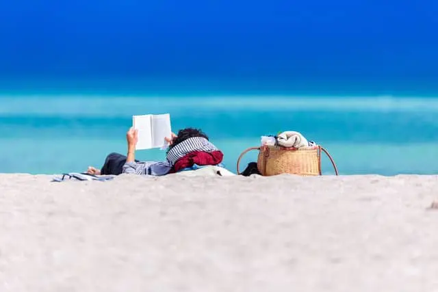 Person reading a book on the beach, relaxing