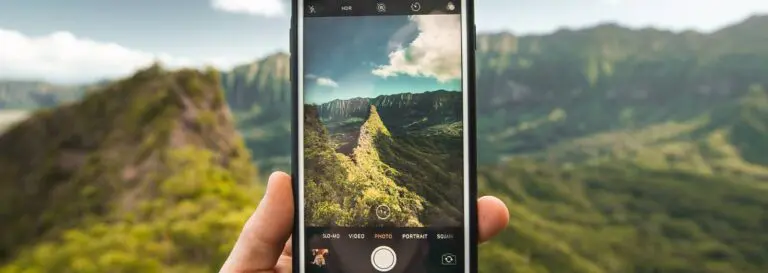 person pointing phone camera at mountains