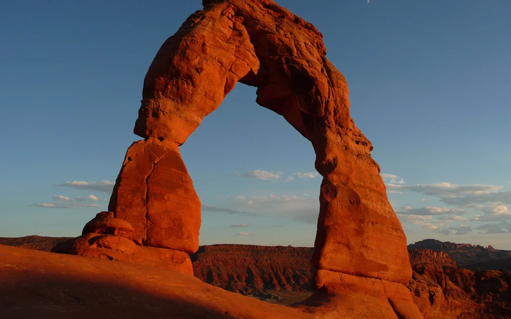 A natural formed arch located in the Arches National Park in Utah. The setting sun gives the rock a copper color.