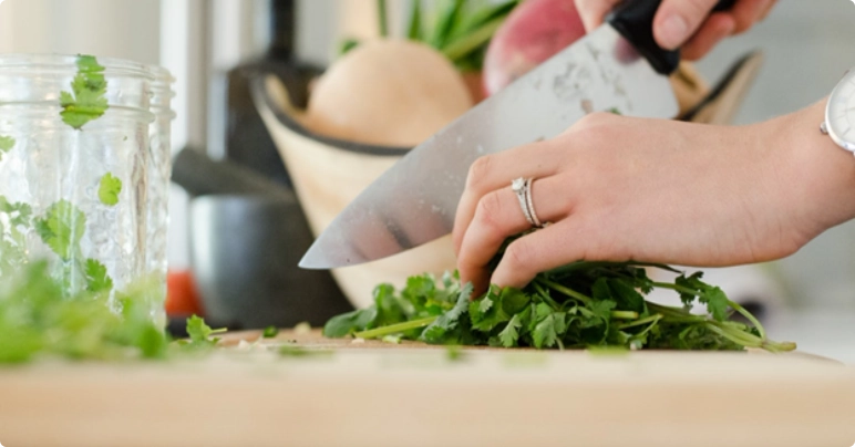 side view of woman chopping parsley on cutting board