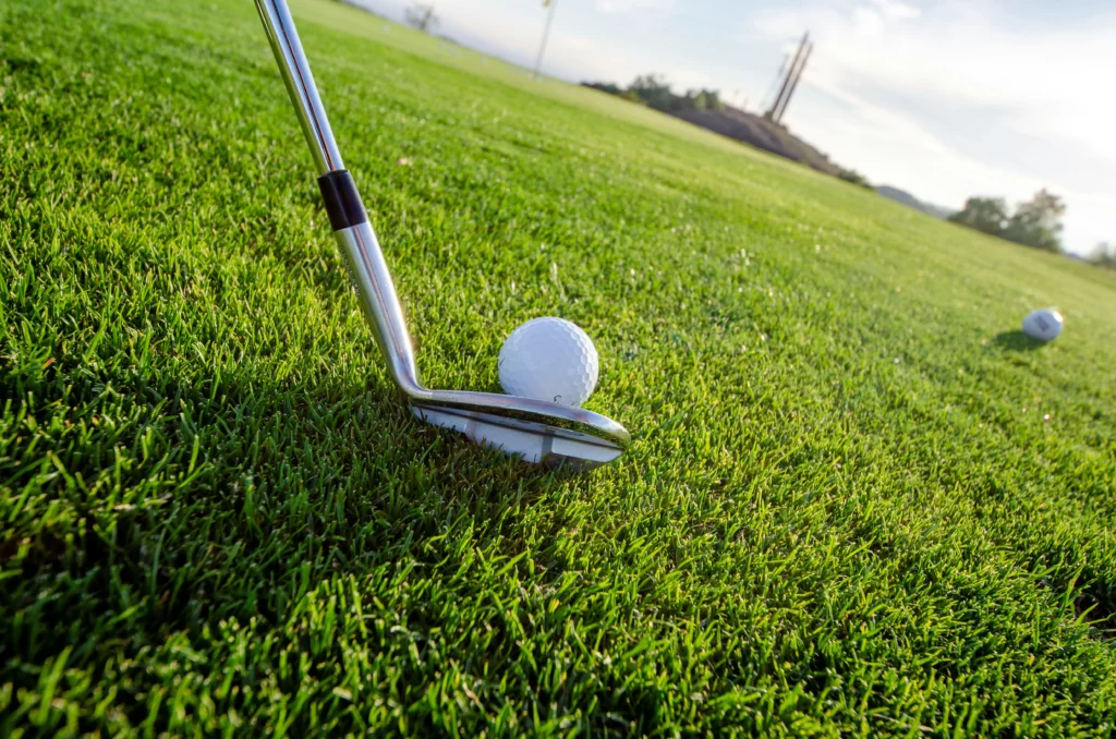 Image shows a golf club gently touching a gold ball