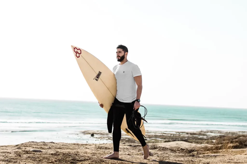 Man walks on beach holding a surfboard